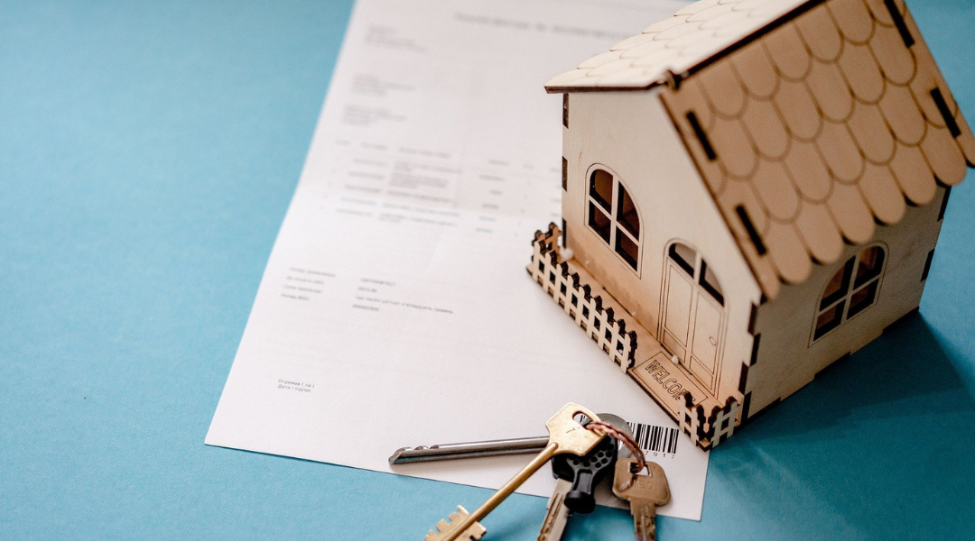 Model wooden house with keys on a contract